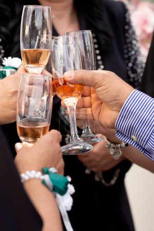 Hands with glasses filled with champagne connect them with the clink of a joyful party event at a social event.