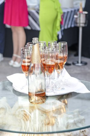 beautifully displayed glasses of sparkling wine and champagne with highlights on a tray at a festive event against the backdrop of dressed up people