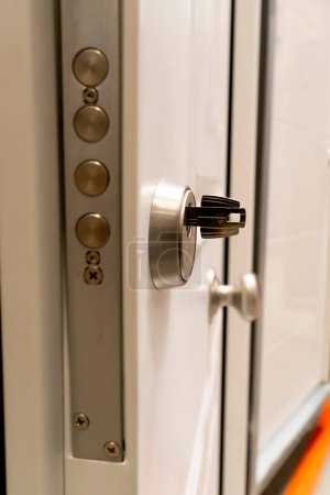 Gros plan d'une clé insérée dans le trou de serrure d'une serrure de porte, vue de l'extrémité. Présentation de meubles et accessoires dans une fenêtre de magasin.