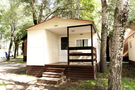 Prefabricated mobile modular container house in forest camping with porch. Temporary house in nature, forest rest