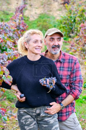 Téléchargez les photos : Jeune couple d'agriculteurs matures dans une ferme viticole avec un bouquet de raisins. Iguzkiza, Navarre, Espagne, Europe. - en image libre de droit