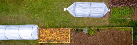 Photo for Aerial view of DIY low tunnel greenhouses in a home garden. Polytunnels, autumn garden, cold weather crop protection background. - Royalty Free Image