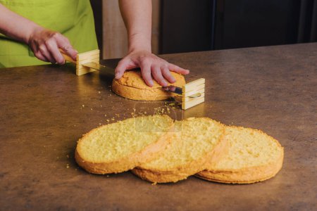 Bäckerin schneidet traditionellen Biskuitkuchen mit speziellem Kuchenmesser in Schichten. DIY, Reihenfolge, Schritt für Schritt.