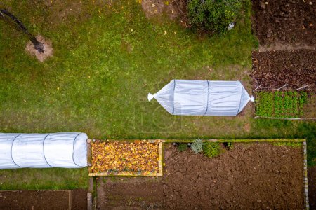 Foto de Vista aérea de invernaderos de túnel bajo de bricolaje en un jardín casero. Polytunnels, jardín de otoño, fondo de protección de cultivos de clima frío. - Imagen libre de derechos