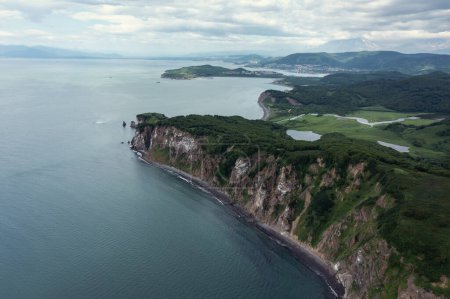 Téléchargez les photos : Photo aérienne de drone du phare Cape sur la péninsule du Kamchatka sur la côte pittoresque de la baie d'Avacha recouverte d'herbe verte dans l'océan Pacifique - en image libre de droit