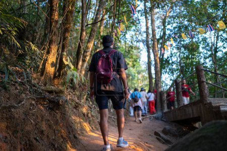 Los turistas asiáticos están subiendo Khao Khitchakut, a través de grandes árboles en el bosque, atracción turística Chanthaburi, Tailandia.