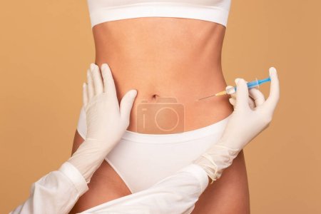 Photo for Beauty treatment. Closeup view of young fit woman getting injection in her belly area, having procedure in salon. Doctor in gloves making jab in stomach - Royalty Free Image