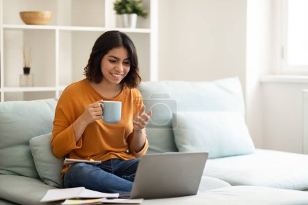 Online Communication. Happy Arab Woman Making Video Call On Laptop And Drinking Coffee At Home, Cheerful Middle Eastern Female Having Teleconference With Friends And Enjoying Hot Drink, Copy Space Poster 619129672
