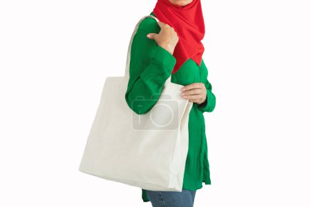 Photo for Close up of muslim female consumer holding blank white eco tote bag, posing over white studio background, copy space. Eco-friendly lifestyle, stop using plastic concept - Royalty Free Image