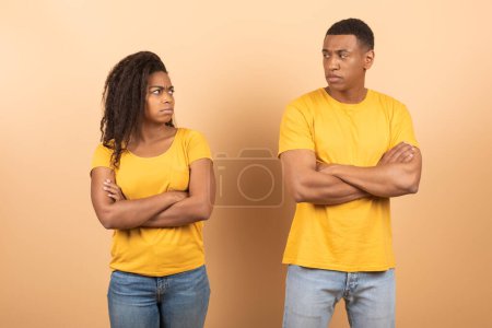 Téléchargez les photos : Jeune couple afro-américain debout mains séparées et croisées sur fond studio pêche. Noir homme et femme ne parlent pas entre eux après la querelle de famille - en image libre de droit