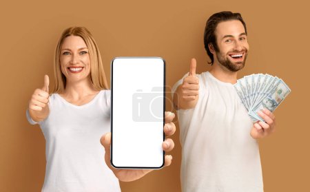 Photo for Happy positive couple enjoying prize, attractive young man and woman in white t-shirts showing cell phone with white empty screen and cash, gesturing thumb ups, gambling online, colorful background - Royalty Free Image