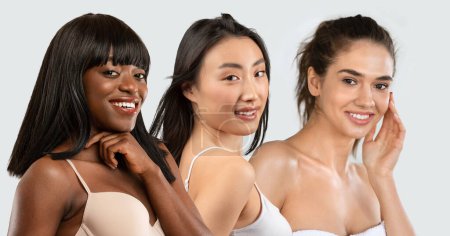 Foto de Cuidado facial de la piel. Mujeres jóvenes multiraciales posando en ropa interior tocando la cara cuidando la piel, aisladas en gris. Sonriendo a la cámara. Concepto de rutina de cuidado de belleza de la piel femenina, Collage - Imagen libre de derechos