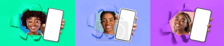 Foto de Tres sonrientes señoras negras bonitas y elegantes que muestran teléfonos inteligentes modernos con pantallas blancas en blanco a través de agujeros rotos en paredes de papel de colores, recomendando una buena oferta, collage, pancarta - Imagen libre de derechos