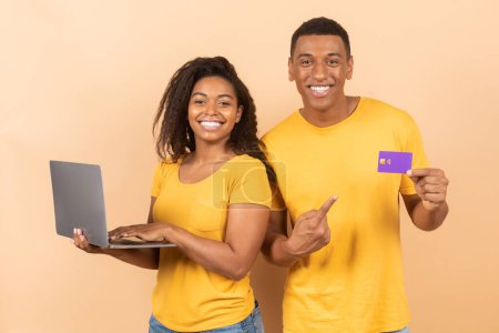 Photo for Online shopping, black friday and payment with money. Happy african american woman holding laptop, guy showing credit card, posing on colorful background, studio shot - Royalty Free Image
