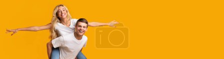 Photo for Handsome teen guy piggybacking his pretty blonde girlfriend, happy millennial couple enjoying time together, posing on yellow studio background, panorama with copy space, collage - Royalty Free Image
