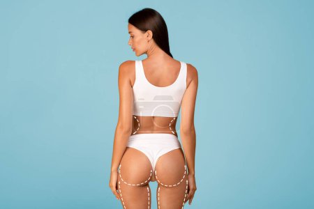 Liposculpture. Rear view of slim woman in white underwear with dashed lines on body standing isolated on blue background, young fit female demonstrating her perfect figure, collage with copy space