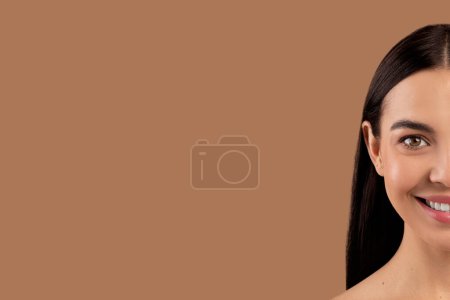 Photo for Half of beautiful brunette long-haired smiling young womans face with perfect skin against beige studio background, panorama with copy space. Cosmetology, face care, aesthetic medicine concept - Royalty Free Image
