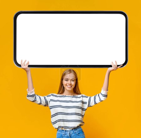 Photo for Great Offer. Beautiful Young Woman Holding Big Blank Smartphone Above Head, Cheerful Millennial Female Demonstrating Mobile Phone With White Screen, Recommending App Or Website, Mockup - Royalty Free Image