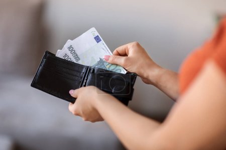 Photo for Closeup Shot Of Young Woman Taking Out Money From Wallet At Home, Unrecognizable Female Pulling Euro Banknotes, Counting Finances While Planning Budget And Spends, Cropped Image With Selective Focus - Royalty Free Image