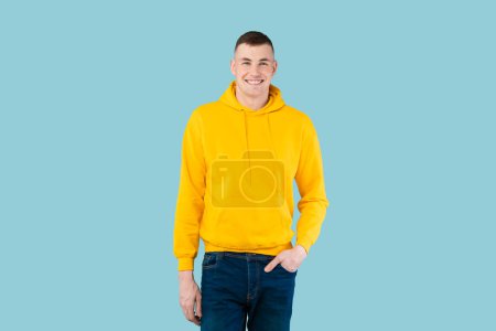 Photo for Happy handsome man posing with hand in pocket and smiling at camera on blue studio background, positive caucasian guy feeling excited, copy space - Royalty Free Image
