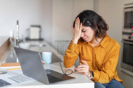 Photo for Failure Concept. Young Arab Woman Having Stress While Working With Laptop Computer At Home, Depressed Middle Eastern Female Freelancer Sitting At Kitchen Counter, Having Problems With Remote Work - Royalty Free Image