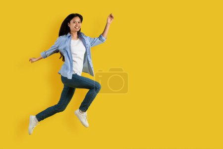 Photo for Satisfied excited cute young asian lady student in casual enjoy freedom, jumping and freezing in air isolated on yellow background, studio. Fashion lifestyle, education, fun, huge sale, ad and offer - Royalty Free Image