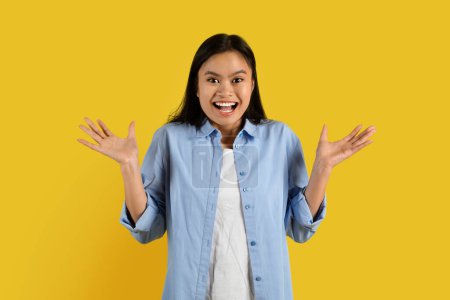 Photo for Happy emotional surprised confused millennial korean female student in casual rejoices to victory and success, isolated on yellow background, studio. Great sale, shock human emotions, ad and offer - Royalty Free Image