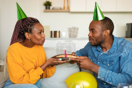 Photo for Young african american couple having cake while celebrating birthday and blowing candles together. Young black spouses having domestic b-day party. Happy birthday honey - Royalty Free Image