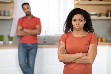 Photo for Offended sad unhappy millennial black woman in red t-shirt ignores husband after quarrel in kitchen interior. Scandal and people emotions at home, relationship problems, stress and domestic violence - Royalty Free Image