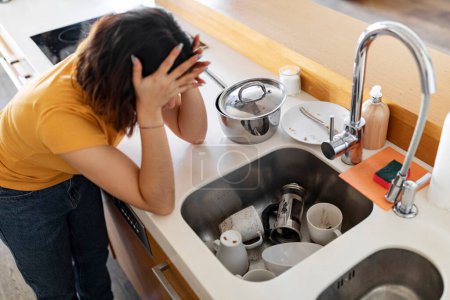 Photo for Stressed Young Woman Touching Head While Looking At Pile Of Dirty Dishes, Upset Millennial Lady Tired Of Making Domestic Chores, Depressed Female Exhausted Of Housekeeping, Above Shot - Royalty Free Image