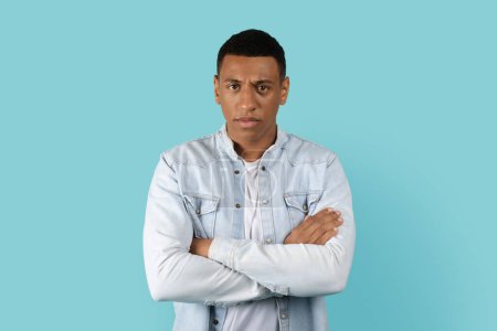 Photo for Angry sad serious displeased young african american man with crossed arms on chest isolated on blue background, studio. Facial expression, emotions of man, problems and stress, lifestyle and skeptic - Royalty Free Image