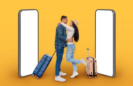 Téléchargez les photos : Aimer beau jeune heureux couple du Moyen-Orient voyageurs avec des valises étreignant, posant par les gros téléphones avec des écrans blancs vierges sur fond jaune, maquette, collage pour escapade, concept de tourisme - en image libre de droit