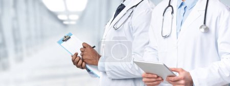 Téléchargez les photos : Soutien médical. Image recadrée de deux médecins masculins avec presse-papiers et tablette numérique dans les mains debout dans la salle d'hôpital, thérapeutes méconnaissables en uniforme prêts à vérifier avec le patient, Collage - en image libre de droit