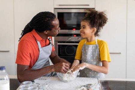 Photo for Black father and preteen daughter preparing dough for cookies in kitchen together, happy african american family baking at home, dad and female child having fun while making pastry, free space - Royalty Free Image
