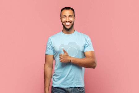 Photo for Happy african american man showing thumb up and cheerfully smiling at camera, posing isolated on pink studio background, recommending nice stuff. Gestures concept - Royalty Free Image