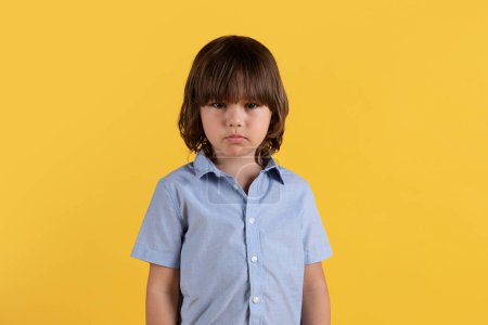 Photo for Child psychotherapy concept. Studio portrait of upset little boy suffering from bullying and society problems, looking sadly at camera, orange background, free space - Royalty Free Image