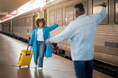 Photo for Happy Young Black Couple Meeting At Railway Station After Arrival, Joyful African American Man And Woman Walking On Platform And Spreading Hands For Hug, Enjoying Long Awaited Meet, Selective Focus - Royalty Free Image