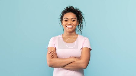 Téléchargez les photos : Portrait of happy african american woman standing with folded arms, looking and smiling at camera, excited black lady posing over blue studio background, panorama - en image libre de droit