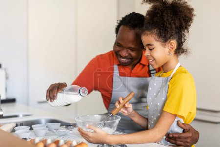 Téléchargez les photos : Happy African American Dad And His Preteen Daughter Baking Pastry In Kitchen Together, Smiling Black Father And Female Child Having Fun While Making Dough For Muffins At Home, Free Space - en image libre de droit