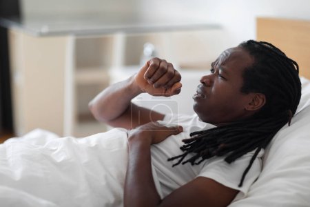 Téléchargez les photos : Portrait Of Ill Black Man Coughing While Lying In Bed At Home, Sick Young African American Male Feeling Unwell, Having Seasonal Flu Or Cold Sympthoms While Resting In Bedroom, Side View, Closeup - en image libre de droit
