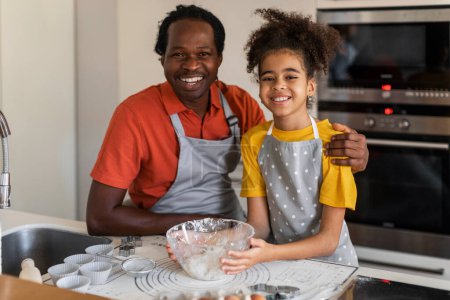 Téléchargez les photos : Happy Black Dad And Daughter Posing At Camera While Baking In Kitchen, Cheerful African American Family Father And Preteen Female Child Having Fun While Cooking Together At Home, Copy Space - en image libre de droit