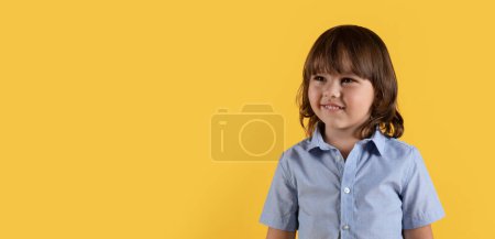 Photo for Kids development products. Adorable happy little boy looking aside at empty space and smiling, enjoying offer, orange studio background, panorama - Royalty Free Image