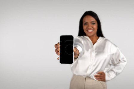 Photo for Cheerful young african american business female show smartphone with blank screen, isolated on white background, studio. App and technology, recommendation for work, business and startup remotely - Royalty Free Image
