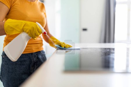 Téléchargez les photos : Young Woman Using Detergent Spray And Rag While Wiping Table In Kicthen, Unrecognizable Housewife Wearing Rubber Gloves Cleaning Counter Surface, Enjoying Tidying Home And Making Domestic Chores - en image libre de droit