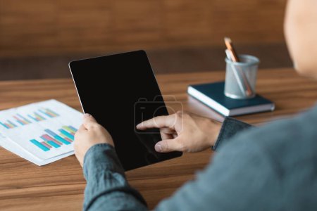 Foto de Adult japanese man use tablet with blank screen, works with charts and graphs, analyzes financial data at workplace in office interior, cropped. Device and app for business, economics, management - Imagen libre de derechos
