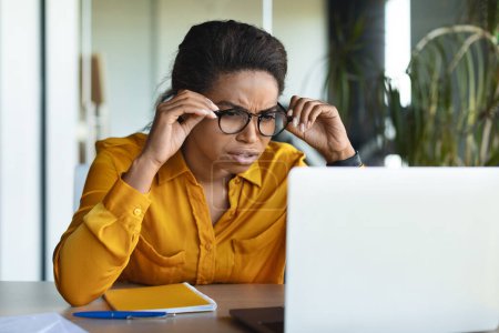 Photo for Poor eyesight. Businesswoman looking at laptop computer, squinting eyes and wearing eyeglasses, having problem with sight, frowning reading negative news, sitting in office - Royalty Free Image