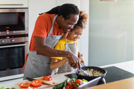 Téléchargez les photos : Loving Black Dad And Preteen Female Child Cooking Together In Kitchen, Happy African American Father And Daughter Preparing Tasty Food In Pan, Enjoying Making Healthy Meal At Home, Copy Space - en image libre de droit