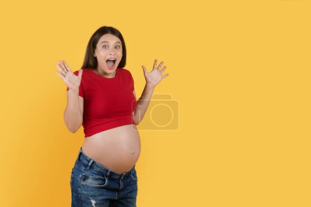 Photo for Big Sale. Portrait Of Amazed Young Pregnant Woman Standing Over Yellow Background, Surprised Expectant Female Spreading Hands And Opening Mouth In Excitement, Enjoying Nice Offer, Copy Space - Royalty Free Image