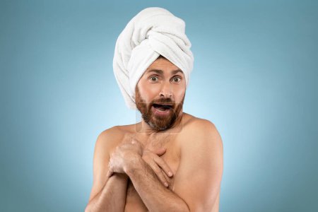 Téléchargez les photos : Funny shy man. Handsome bearded guy with towel on head standing on blue background, putting hands on his chest and looking at camera - en image libre de droit