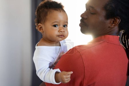 Photo for Fathers Day Concept. Young Black Man Holding Cute Little Baby On Hands, Loving African American Dad Bonding With His Adorable Infant Son Or Daughter At Home, Toddler Child Looking At Camera - Royalty Free Image